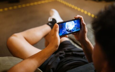 Man playing a video game on a smartphone while sitting comfortably indoors.